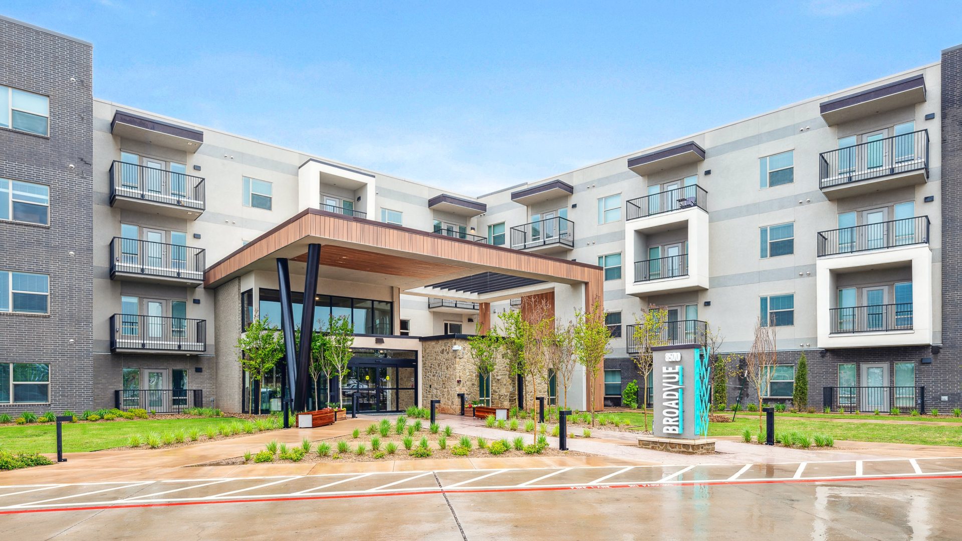 the exterior of an apartment building with a parking lot at The BroadVue